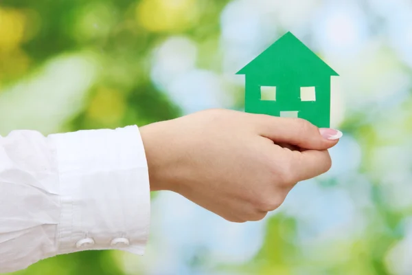 Concept: woman hand with paper house on green background, close up — Stock Photo, Image