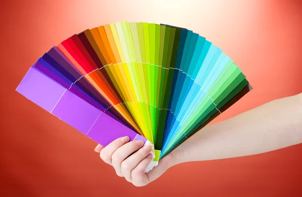 Hand holding bright palette of colors on red background — Stock Photo, Image