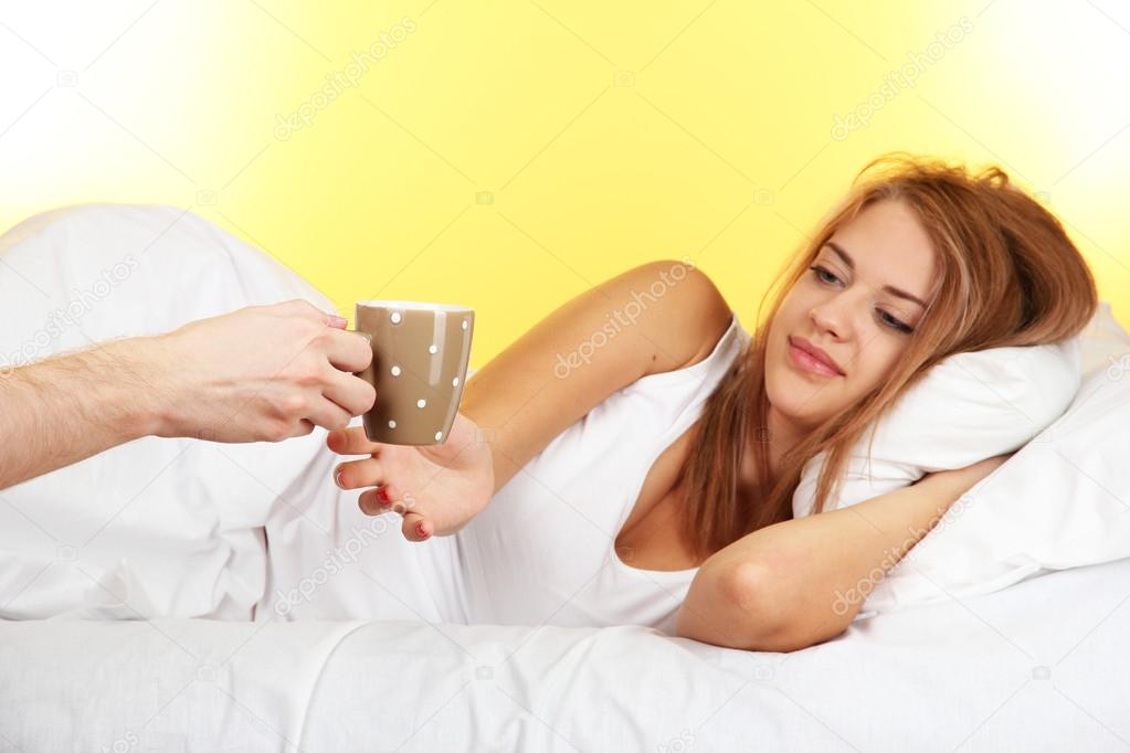 morning coffee in bed for young woman on yellow background