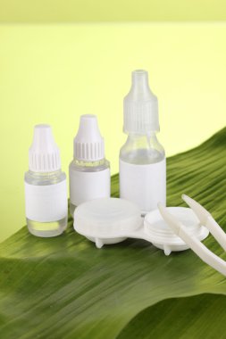 Göz damlaları ve yaprak yeşil zemin üzerine lensler