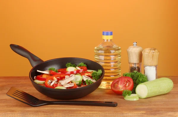 Frying pan with vegetables on red background — Stock Photo, Image