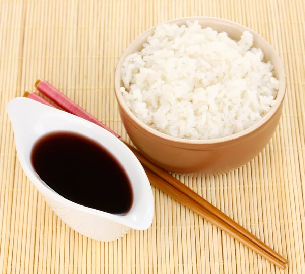 Kom rijst en eetstokjes op bamboe mat — Stockfoto