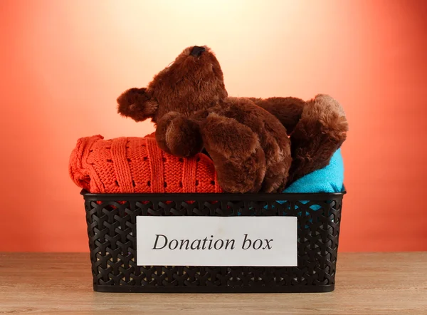 Scatola di donazione con vestiti su sfondo rosso primo piano — Foto Stock