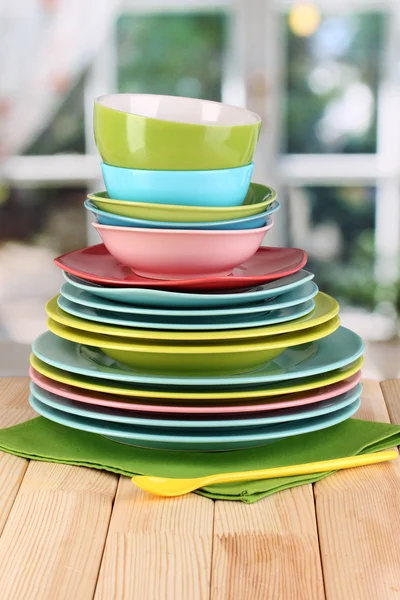 Colorful tableware on wooden table on window background — Stock Photo, Image