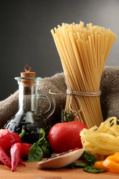 Pasta spagetti, grönsaker och kryddor, på träbord, på grå bakgrund — Stockfoto