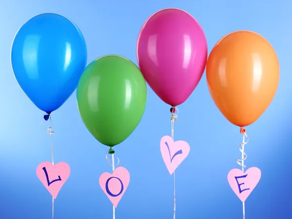 Kleurrijke ballonnen houdt woord liefde op blauwe achtergrond — Stockfoto