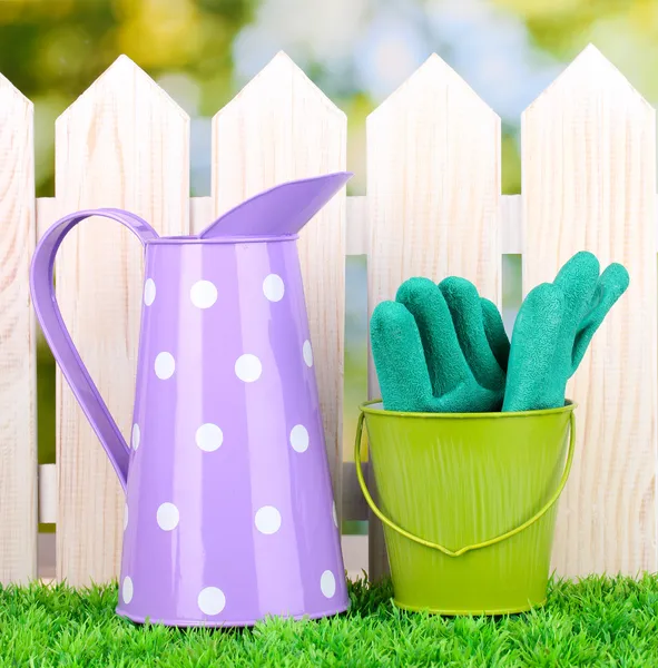 Gardening tools on green grass on wooden fence background — Stock Photo, Image