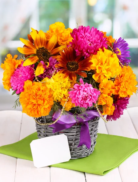 Beautiful bouquet of bright flowers with paper note on wooden table on window background — Stock Photo, Image