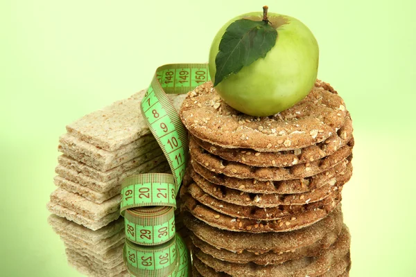 Mumsiga knäckebröd, äpple och måttband, på grön bakgrund — Stockfoto
