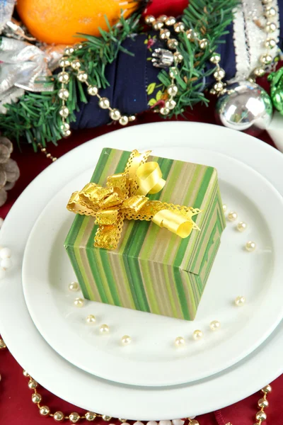 Small Christmas gift on plate on serving Christmas table background close-up — Stock Photo, Image
