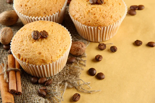 Välsmakande muffin kakor på säckväv, kryddor och kaffe frön, på beige bakgrund — Stockfoto