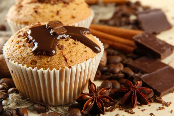 Tasty muffin cakes with chocolate, spices and coffee seeds, close up — Stock Photo, Image