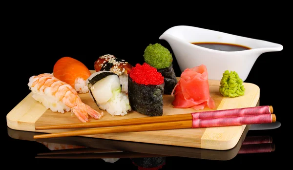 Delicioso sushi servido en tablero de madera aislado en negro —  Fotos de Stock