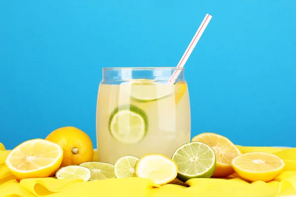 Citrus lemonade in glass bank of citrus around on yellow fabric on blue background — Stock Photo, Image