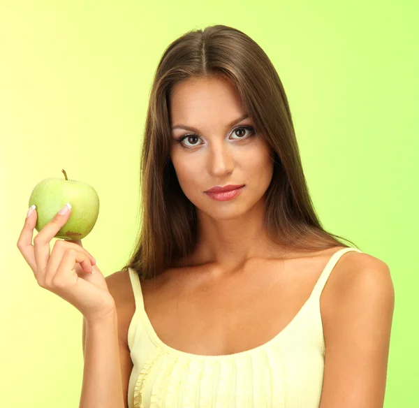 Schöne junge Frau mit grünem Apfel, auf grünem Hintergrund — Stockfoto