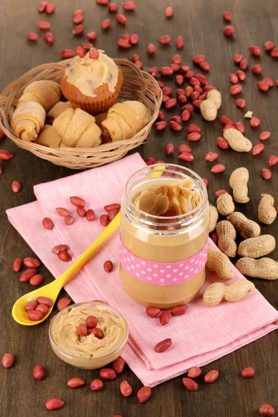 Deliciosa manteiga de amendoim em jarra com cozimento em guardanapo em mesa de madeira close-up — Fotografia de Stock