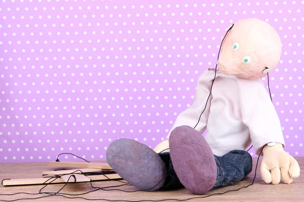 Houten marionet zittend op polka dot achtergrond — Stockfoto