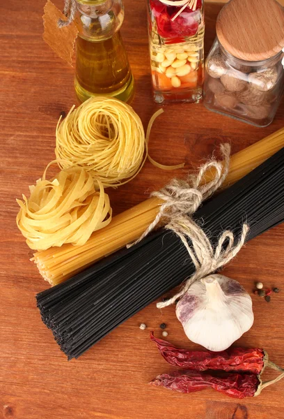 Esparguete de massas, legumes e especiarias na mesa de madeira no fundo de madeira — Fotografia de Stock