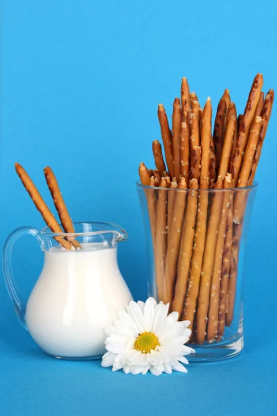 Leckere knusprige Sticks im Glasbecher auf blauem Hintergrund — Stockfoto