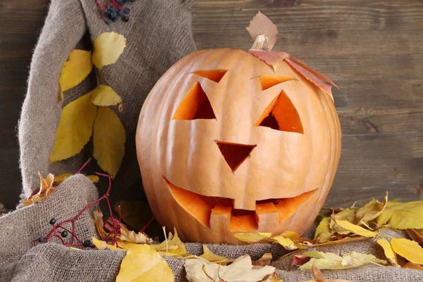 Halloween pompoen en herfst bladeren, op houten achtergrond — Stockfoto