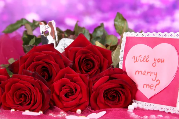 Beautiful bouquet of roses with valentine on pink fabric on purple background close-up — Stock Photo, Image