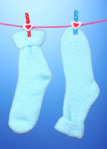 Blauw paar sokken hangen om te drogen op blauwe achtergrond — Stockfoto