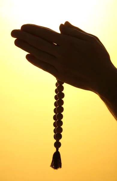 Male hands with rosary, on yellow background — Stock Photo, Image