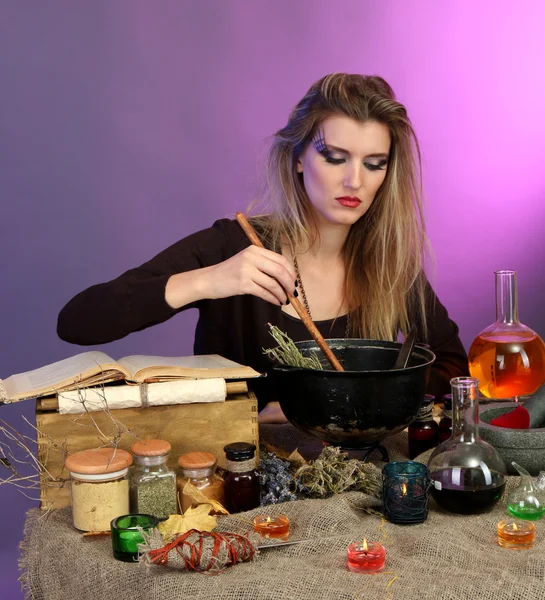 Halloween häxa omrörning i gift soppa i sin kittel på färgbakgrund — Stockfoto