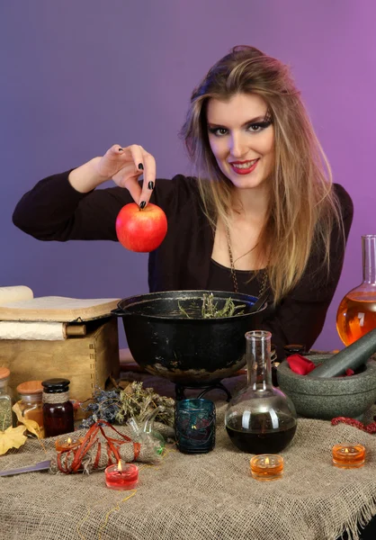 Halloween-Hexe bereitet Giftsuppe in ihrem Hexenkessel auf farbigem Hintergrund zu — Stockfoto