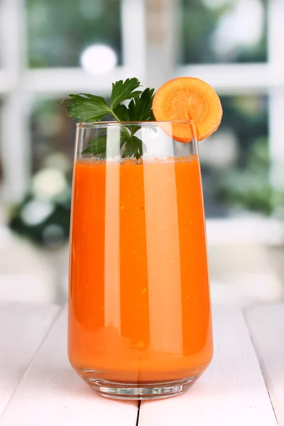 Glass of carrot juice on wooden table, on window background — Stock Photo, Image