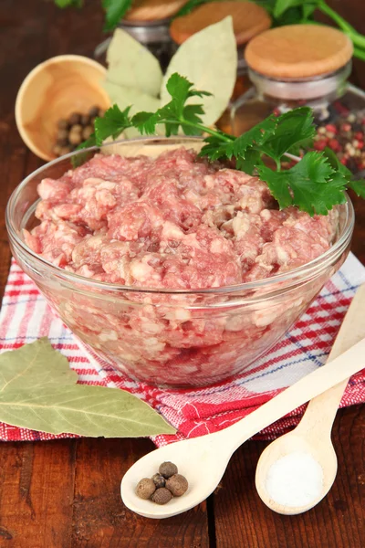 Bowl of raw ground meat with spices on wooden table — Stock Photo, Image