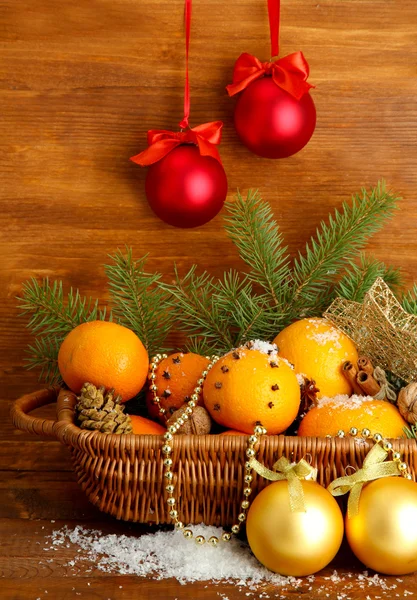 Composição de natal em cesta com laranjas e abeto, sobre fundo de madeira — Fotografia de Stock