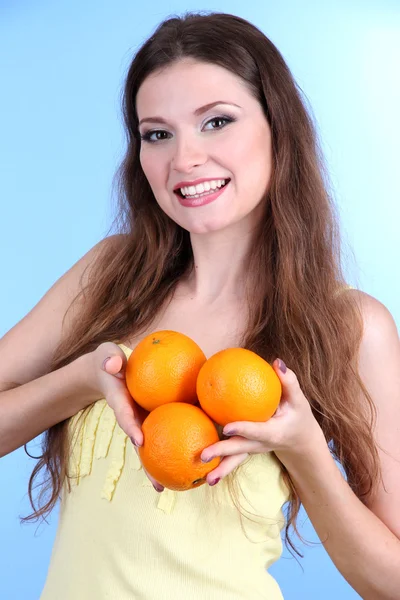 青色の背景にオレンジを持つ美しい女性 ストックフォト