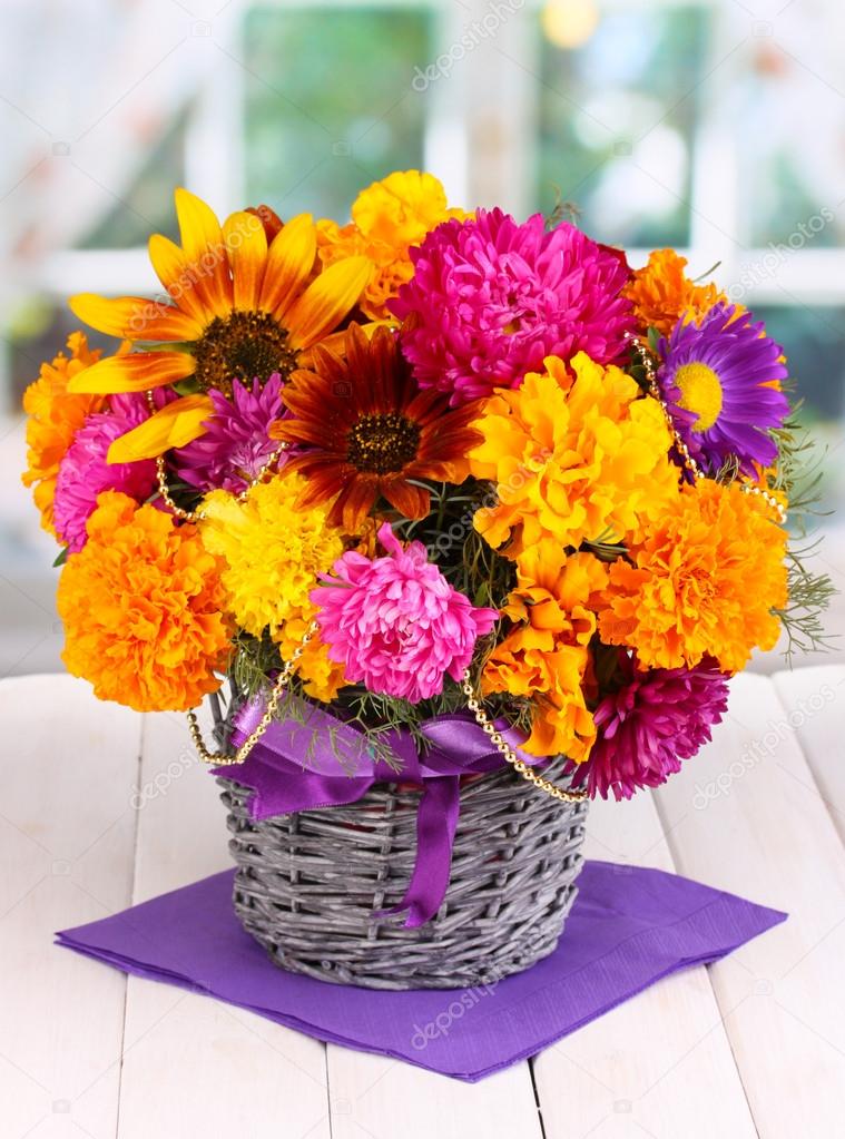 Beautiful bouquet of bright flowers on wooden table on window background