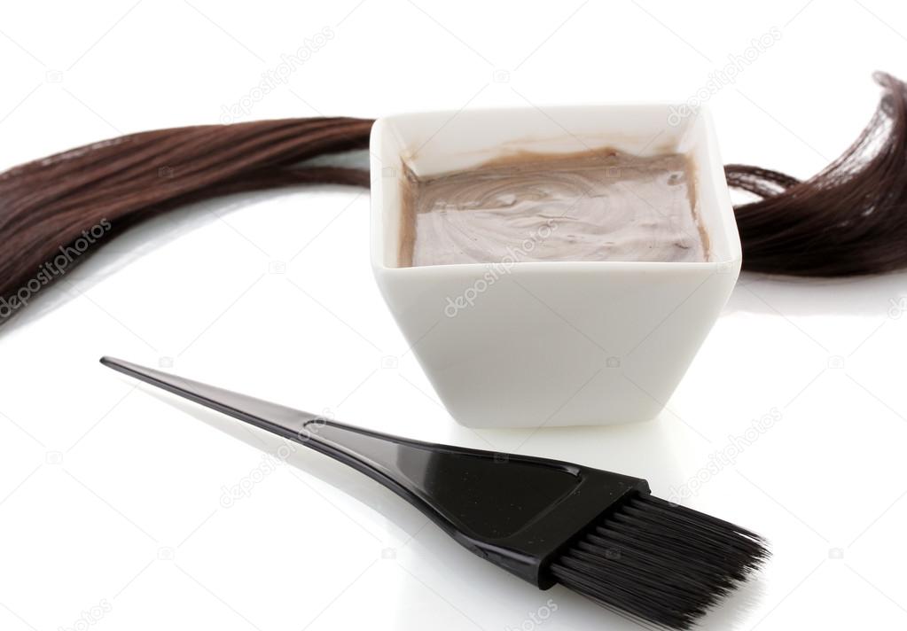 Bowl with hair dye and black brush on white background close-up