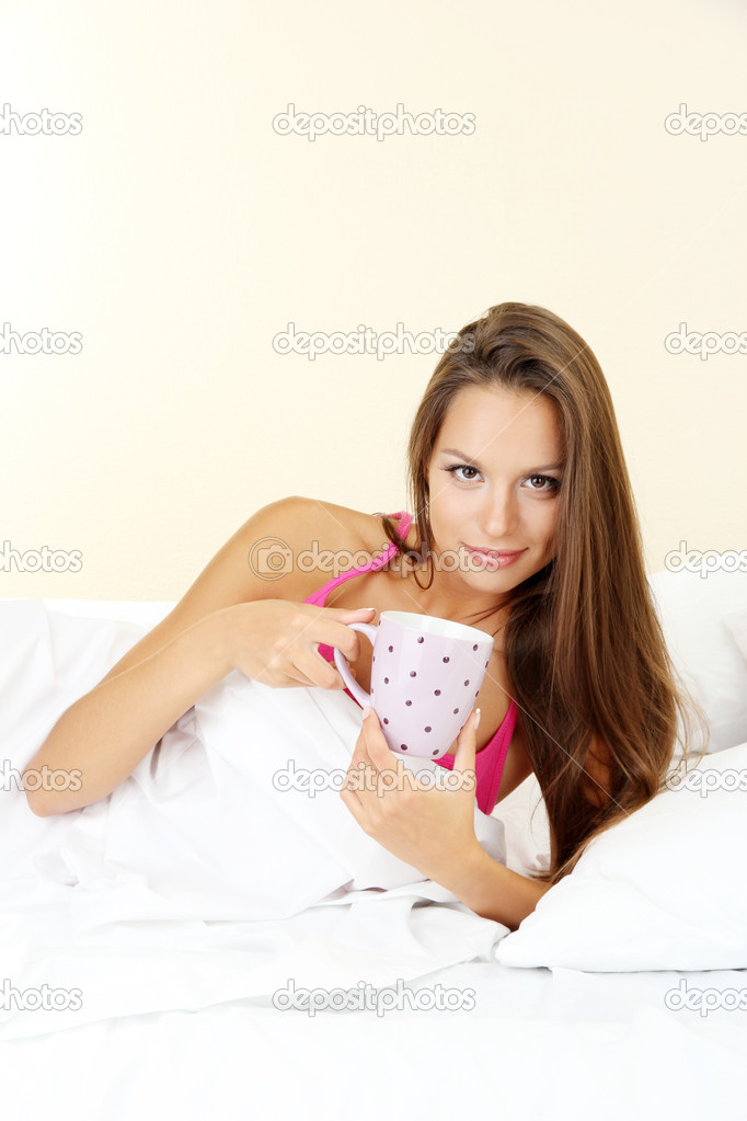 young beautiful woman with cup in bed