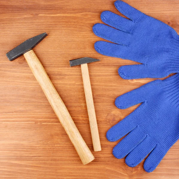 Hammers and gloves on wooden background — Stock Photo, Image