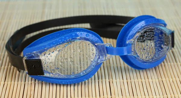 Gafas de baño azules con gotas en una almohadilla de bambú — Foto de Stock