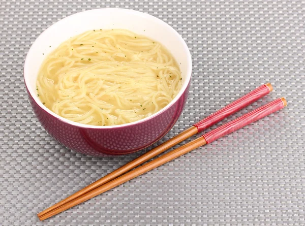 Fideos asiáticos en tazón en estera gris —  Fotos de Stock