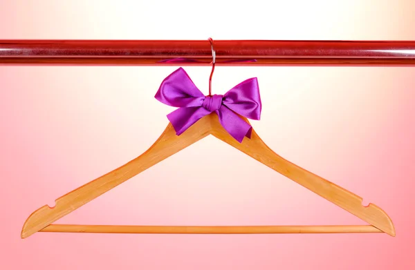 Beautiful purple bow hanging on wooden hanger on pink background — Stock Photo, Image