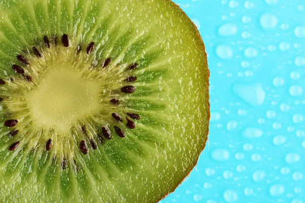 Fatia de kiwi com gota no fundo azul — Fotografia de Stock