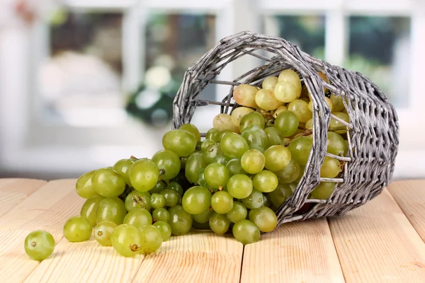 Uvas verdes maduras en cesta sobre mesa de madera sobre fondo de ventana —  Fotos de Stock