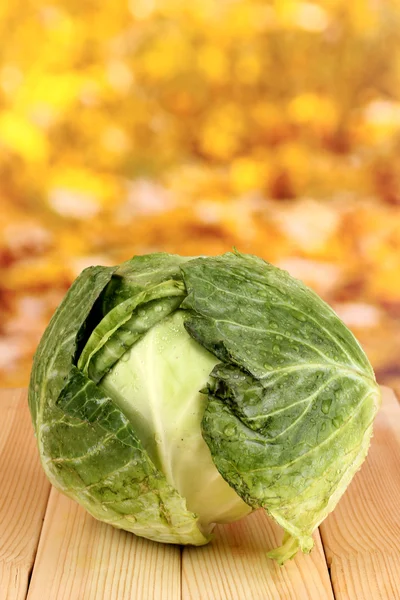 Fresh cabbage on wooden table on colorful background — Stock Photo, Image