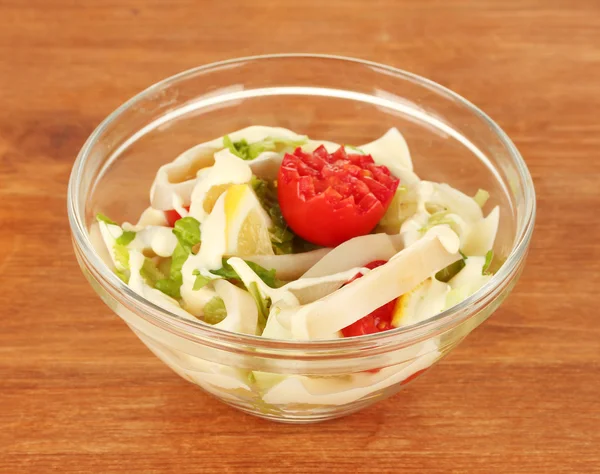 Squid salad with vegetables in a glass bowl on wooden background close-up — Stock Photo, Image