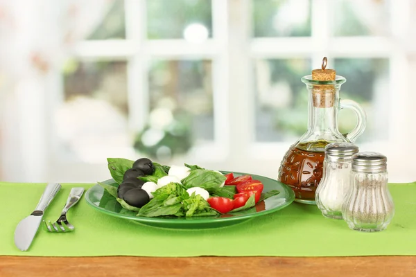Queso mozzarella con verduras en el plato con tenedor y cuchillo en la mesa de madera —  Fotos de Stock