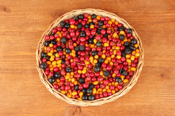 Colorful autumn berries on wicker mat on wooden background close-up — Stock Photo, Image