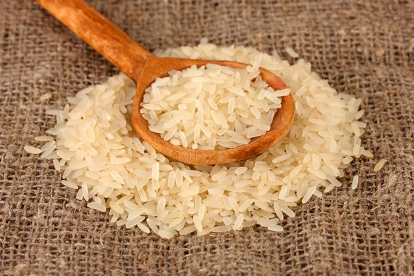 Rice on sacking in wooden spoon — Stock Photo, Image