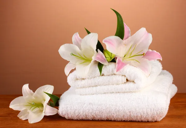 Stapel handdoeken met roze lelie op een bruine achtergrond — Stockfoto