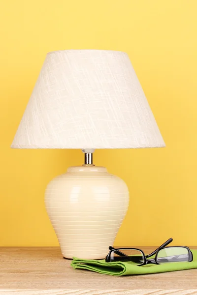 Table lamp and glasses on yellow background — Stock Photo, Image