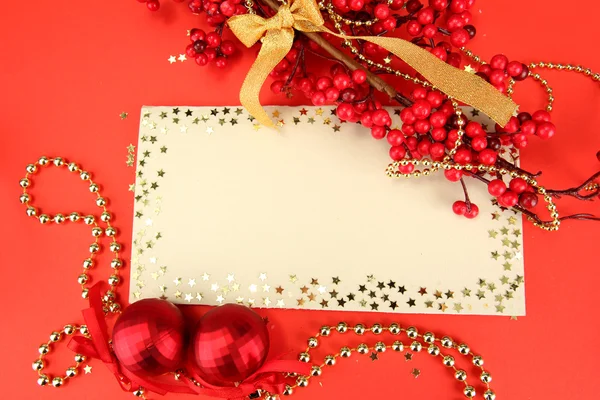 Belas bolas de Natal brilhantes e cartão postal vazio no fundo vermelho — Fotografia de Stock